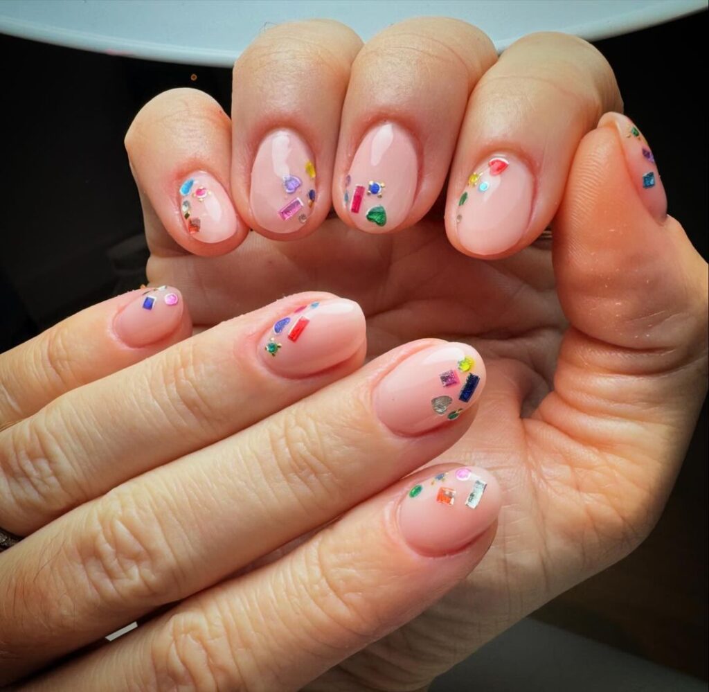 unhas curtas cor-de-rosa com pedras preciosas