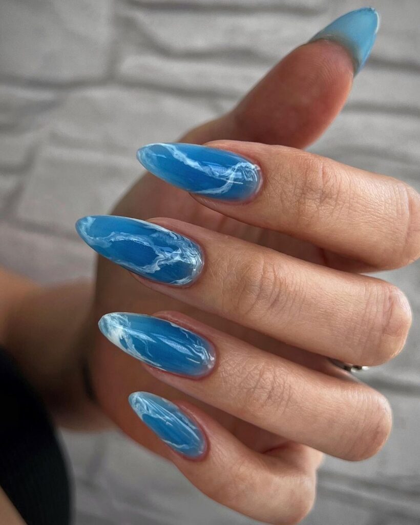 white swirls on blue base nails