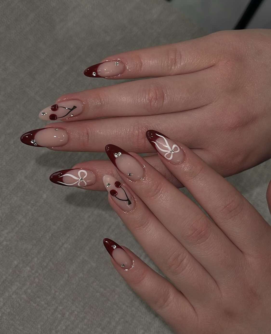 Design de unhas com laço vermelho cereja