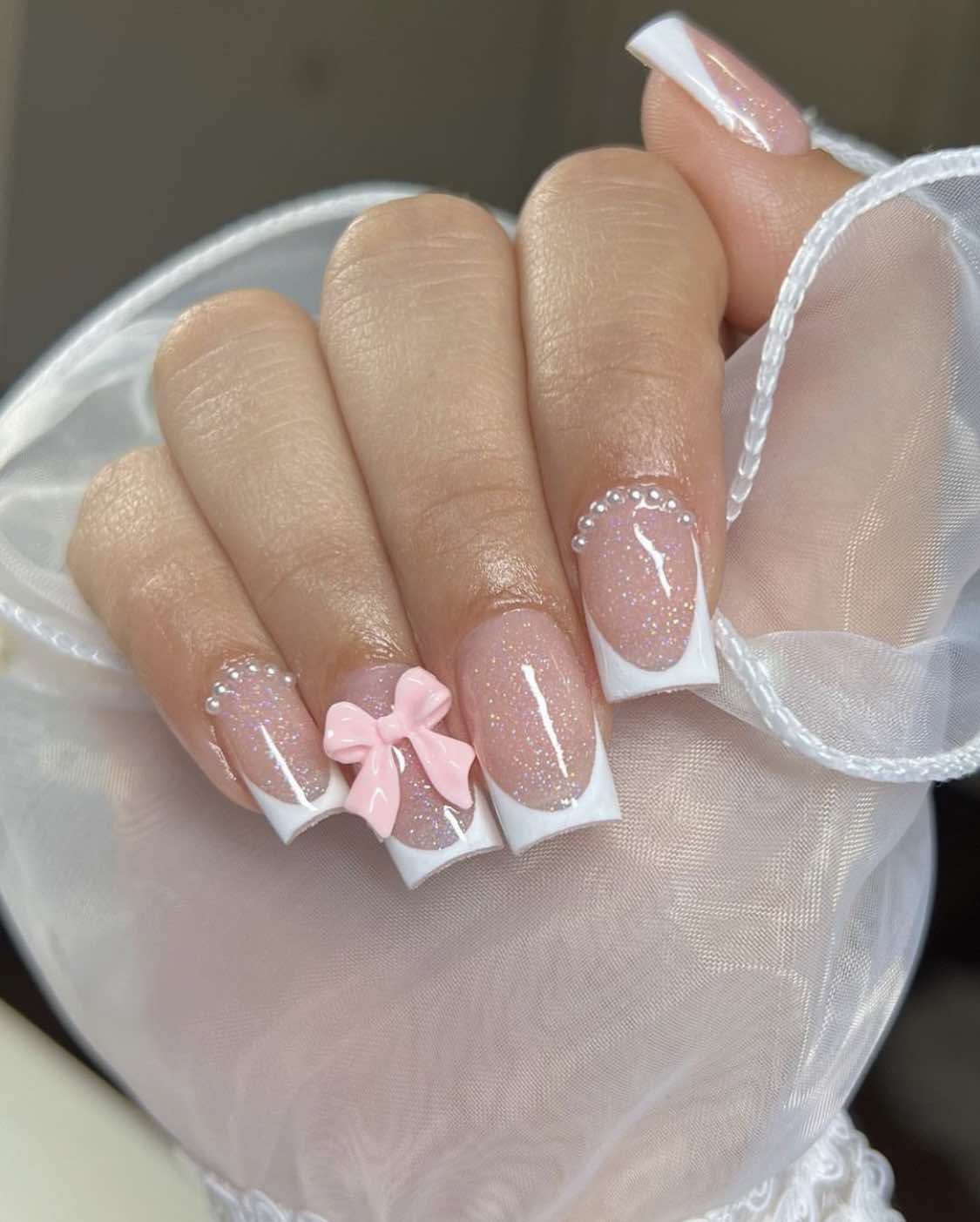 Design d'ongles avec nœud français et paillettes